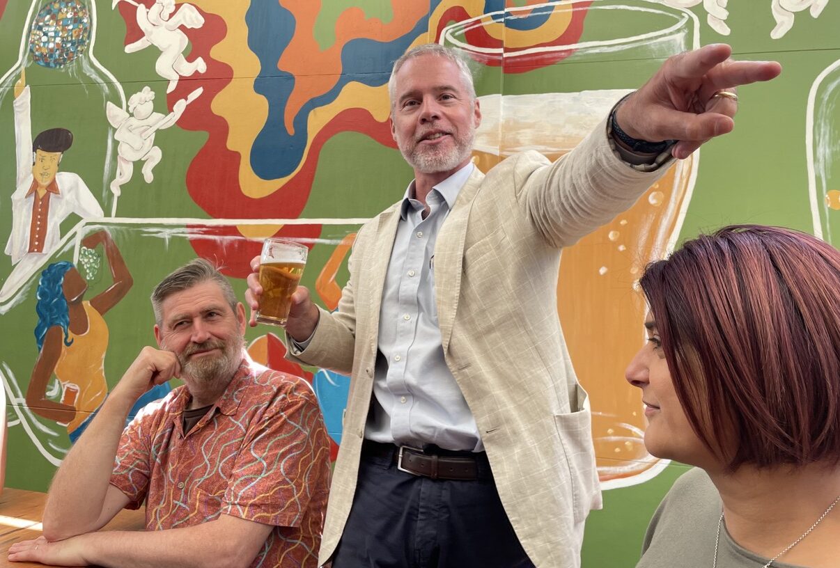 Ben Eggleton holding a glass of beer and giving a speech.